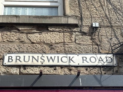 A road sign on a stone wall that says 'Brunswick Road. '