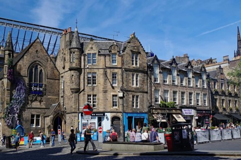 Historic buildings on a busy street with people and sunshine, Haymarket, Royal Mile, Edinburgh,