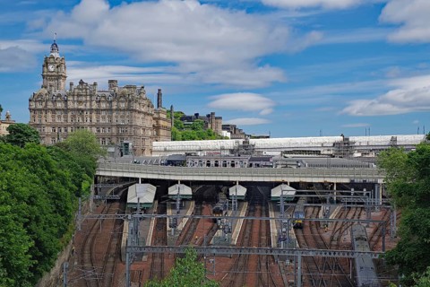 A train station with railroad tracks and an imposing building in the background, Waverley Station,