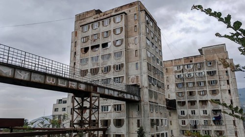 Three high-rise buildings connected by metal bridges under cloudy skies, nostalgic charm,