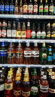Shelves filled with various beverage bottles, beer selection in a Georgian supermarket, Tbilisi,