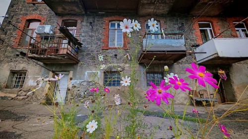 Colourful flowers in front of an old residential building with brick and wood, Armenia