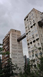 High-rise concrete buildings connected by metal bridges under cloudy sky, nostalgic charm,