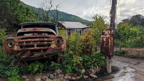 An old, rusty truck stands in front of a power pole in a green setting, romantic, rural atmosphere,