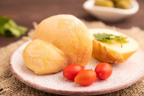 Smoked Mozzarella cheese, with tomatoes and olives on brown wooden background and linen textile,