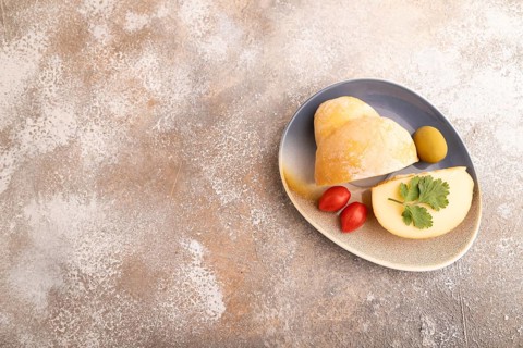 Smoked Mozzarella cheese, with tomatoes and olives on brown concrete background, top view, flat