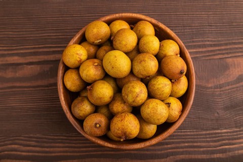 Ripe Longan in wooden bowl on brown wooden background, Top view, flat lay, close up, minimalism
