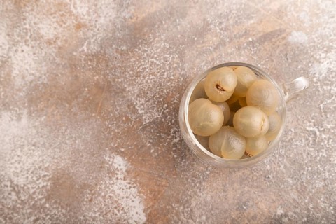 Ripe peeled Longan in glass on brown concrete background, top view, flat lay, copy space,