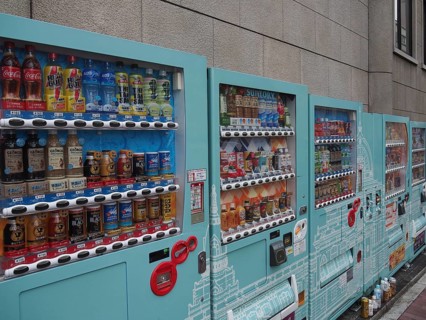 Row of colorful vending machines on a gray wall with a wide selection of drinks, Tokyo, Japan