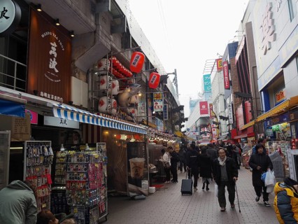 Bustling shopping street with shops and people decorated with red lanterns and signs, Ameyoko