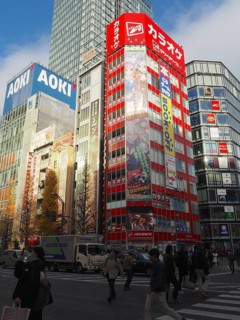 Bustling city street with tall buildings and colorful billboards in daylight, Akihabara Electric