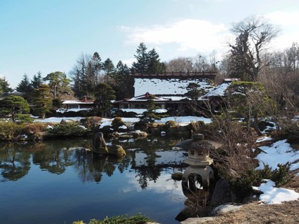 Snowy Japanese garden with small ponds and traditional buildings in the background, Oshino Hakkai,