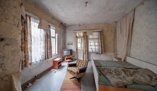 Abandoned hotel room with bed, armchair and television in a dilapidated hotel, Lost Place,