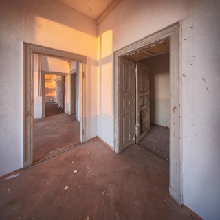 View through the open doors of an abandoned administration building in the light of the evening