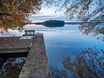 Quiet lake in autumn after sunset at dusk, colorful foliage lying on a jetty, Großer Lychensee,