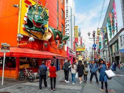 Dragon figure at a restaurant, lots of colorful signs in a pedestrian zone with shops and