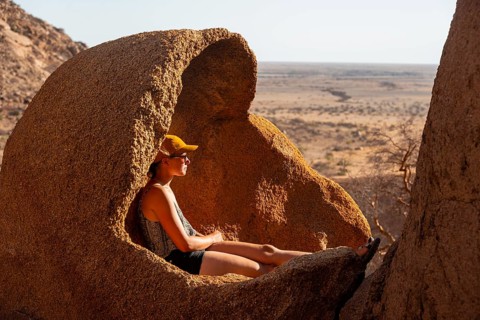 Person sitting relaxing in a natural rock area and enjoying the view of the desert, Spitzkoppe,