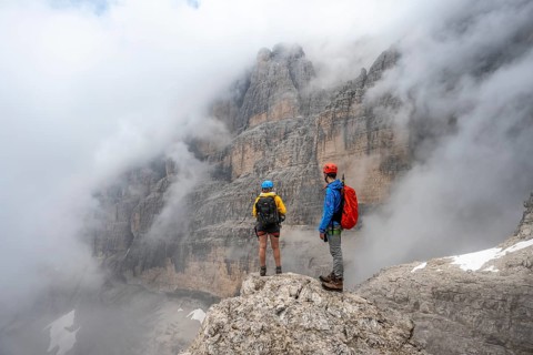 Climbers on the Via Ferrata Oliva Detassis via ferrata in fog, rocky mountain peaks and mountain