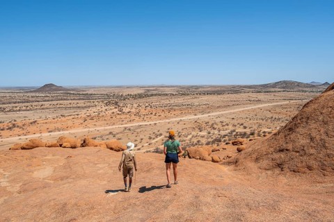Bushman's paradise, tourist and guide hiking through the vast, dry desert landscape, Spitzkoppe,