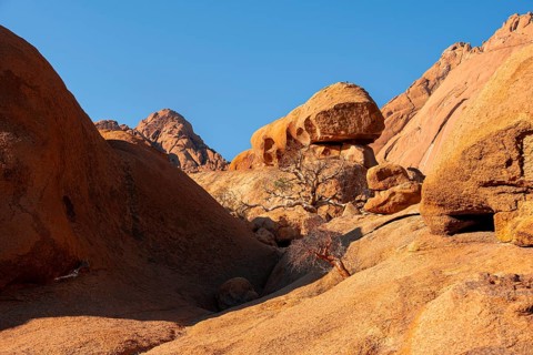 Rocky landscape with orange rocks under clear blue sky, Spitzkoppe, Namibia