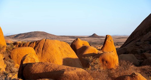 Extensive rock formations and barren desert landscape under clear skies in Spitzkoppe, Spitzkoppe,