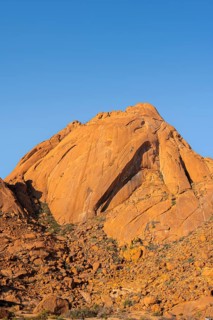 Hilly rock formation rising against the blue sky in the dry desert, Spitzkoppe, Namibia