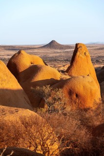 Sun-irradiated rocks offer views of the vast, barren landscape of the Spitzkoppe Desert,