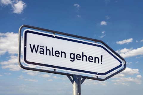 (Photomontage) Directional arrow with the inscription DIAL GO against a blue sky