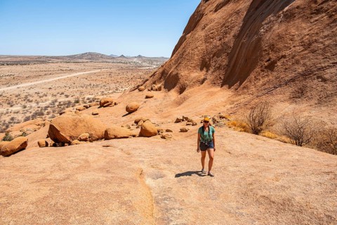 Female hiker explores an impressive rocky landscape in the Namibian desert, Spitzkoppe, Namibia