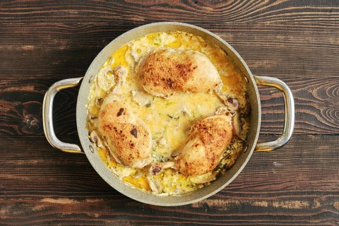 Tree pieces of chicken in a pot filled with creamy mustard mushroom sauce and vegetables. The pot