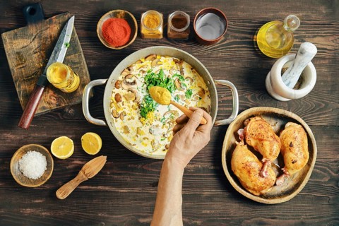 A person adds cardamon into pan with chopped mushrooms, onion, herbs and cream. Adding flavour to