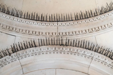 Stone arches with decorative ornaments and long metal spikes to repel pigeons, Royal Academy of