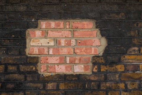 Partially repaired brick wall with contrast of old and new stones, London, England, Great Britain