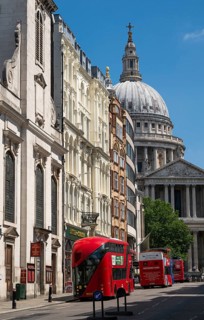 Red double-decker buses on Lugate Hill Street with historic buildings and the dome of St. Paul's