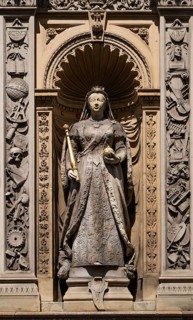 Queen statue with scepter and orb surrounded by decorative elements depicting Queen Victoria,