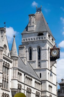 Royal Courts of Justice, neo-gothic architecture with tower and clock under blue sky, London,