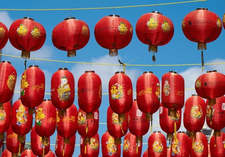 Red Chinese lanterns hanging on yellow lines against a blue sky, London, England, Great Britain