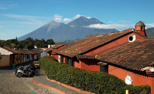 Traditional houses in a cobblestone alley with the Fuego volcano in the back, Old Town, Antigua,
