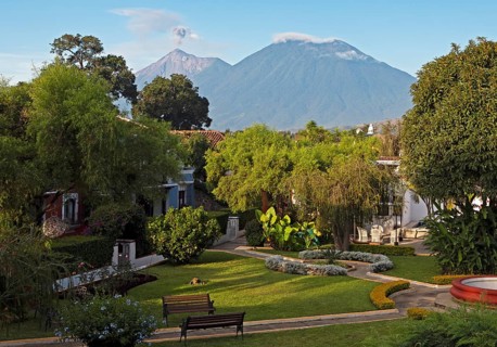 Garden of the Hotel Villa Colonial in the old town, the smoking volcano Fuego in the back, Antigua,
