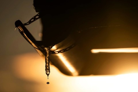 A drop of water comes off an icicle on a gutter in warm sunlight, back light, winter, Korpoström,