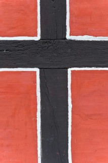 Close-up of a timber-frame structure with red background and black bars, nave, reconstructed