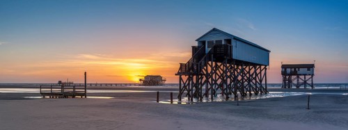 Stilt houses at low tide on the beach at sunset, St. Peter-Ording, Schleswig-Holstein Wadden Sea