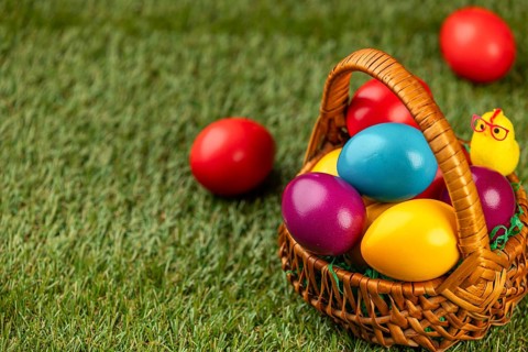 A basket full of colorful Easter eggs on a grassy area