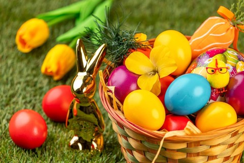 A basket with colorful eggs, flowers and Easter decoration in a meadow