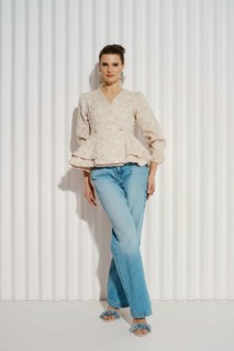 A model stands confidently in a well-fitted top and jeans. She has her left hand on her hip and her