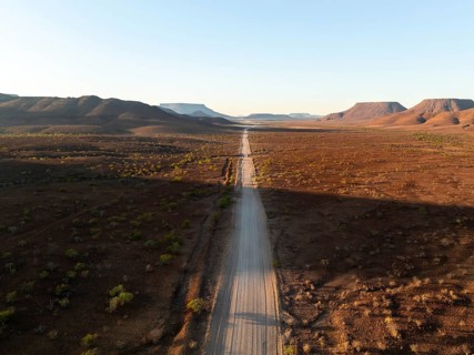Aerial view, infinite space, straight road leads through dry desert landscape, hills in Damaraland,