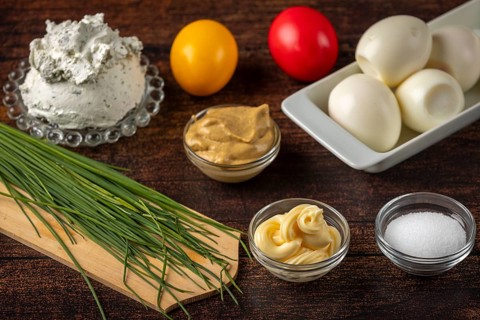 Fresh ingredients, such as herbs, cream cheese and eggs on a wooden table