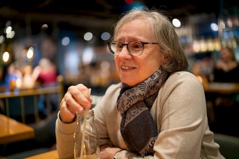 Elderly woman, portrait, glasses, gray hair, scarf, drink, straw, sitting in a bar, restaurant,