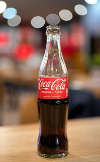 Coke, Coca-Cola, bottle, 0.3 liter, half full, half empty, standing on a table, restaurant, bar,