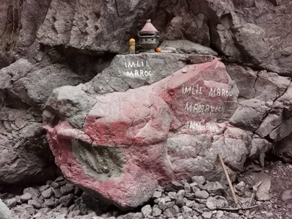 A rock with red and white inscriptions and small decorative objects, welcome, Atlas, Imlil, Morocco